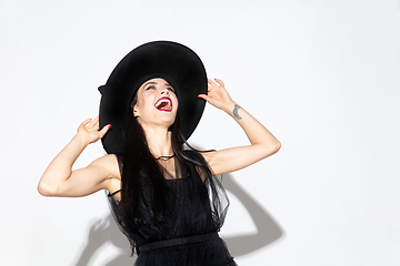 Image showing Young woman in hat and dress as a witch on white background