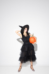 Image showing Young woman in hat and dress as a witch on white background