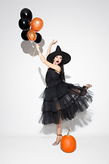 Image showing Young woman in hat and dress as a witch on white background