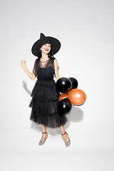 Image showing Young woman in hat and dress as a witch on white background