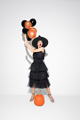 Image showing Young woman in hat and dress as a witch on white background