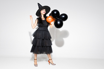 Image showing Young woman in hat and dress as a witch on white background