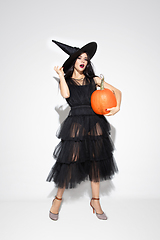 Image showing Young woman in hat and dress as a witch on white background