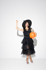 Image showing Young woman in hat and dress as a witch on white background