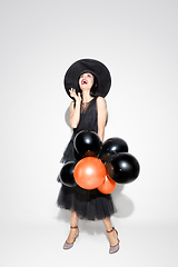 Image showing Young woman in hat and dress as a witch on white background