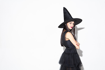 Image showing Young woman in hat and dress as a witch on white background