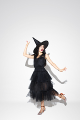 Image showing Young woman in hat and dress as a witch on white background