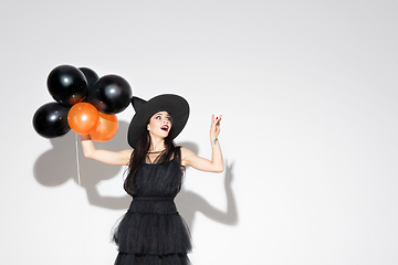 Image showing Young woman in hat and dress as a witch on white background