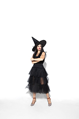 Image showing Young woman in hat and dress as a witch on white background