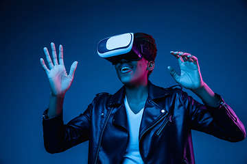 Image showing Young african-american woman\'s using VR-glasses in neon light