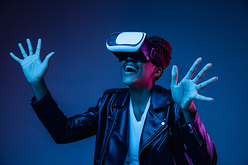 Image showing Young african-american woman\'s using VR-glasses in neon light