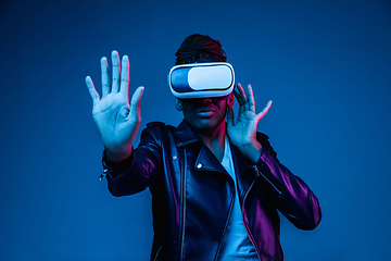 Image showing Young african-american woman\'s using VR-glasses in neon light