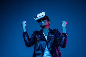 Image showing Young african-american woman\'s using VR-glasses in neon light