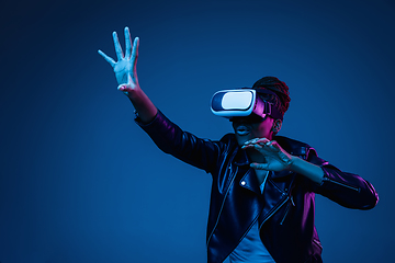 Image showing Young african-american woman\'s using VR-glasses in neon light