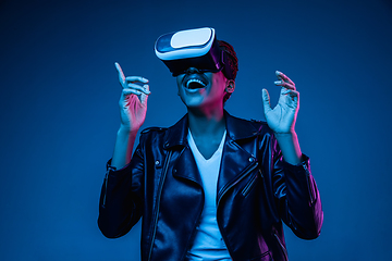 Image showing Young african-american woman\'s using VR-glasses in neon light