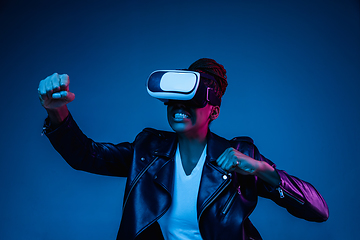 Image showing Young african-american woman\'s using VR-glasses in neon light