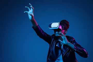 Image showing Young african-american woman\'s using VR-glasses in neon light