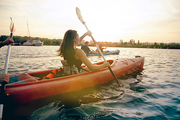 Image showing Happy friends kayaking on river with sunset on the background