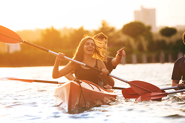 Image showing Confident young couple kayaking on river together with sunset on the background