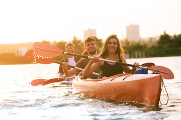 Image showing Happy friends kayaking on river with sunset on the background