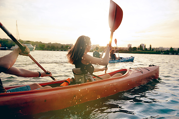 Image showing Happy friends kayaking on river with sunset on the background