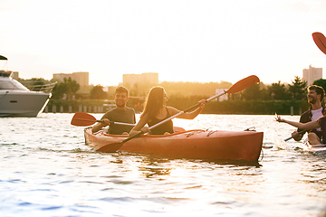 Image showing Happy friends kayaking on river with sunset on the background