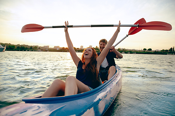 Image showing Confident young couple kayaking on river together with sunset on the background