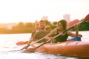 Image showing Happy friends kayaking on river with sunset on the background