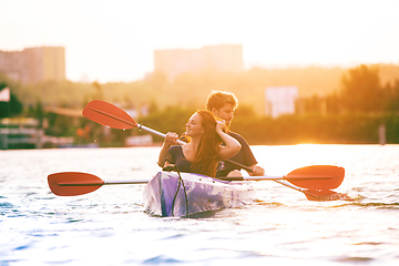 Image showing Confident young couple kayaking on river together with sunset on the background