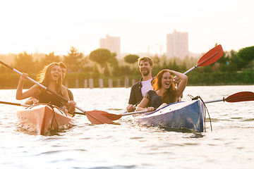 Image showing Happy friends kayaking on river with sunset on the background