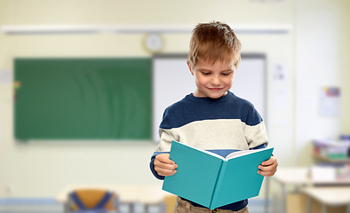 Image showing smiling little boy reading book at school