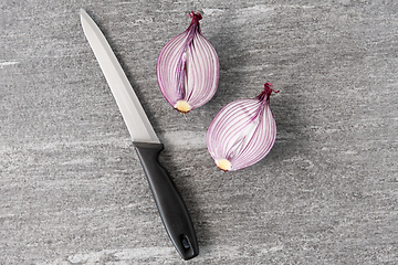 Image showing cut red onion and knife on slate stone background