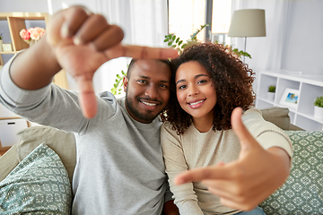 Image showing happy couple making selfie frame gesture at home