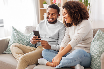 Image showing happy couple with smartphone and earphones at home