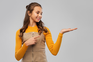 Image showing happy teenage girl holding something on empty hand