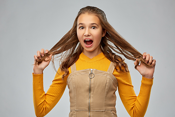 Image showing scared young teenage girl holding her hair strands