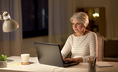 Image showing senior woman with laptop at home in evening