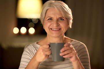 Image showing happy senior woman with cup of tea at home