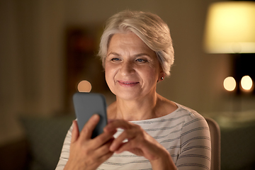 Image showing happy senior woman with smartphone at home