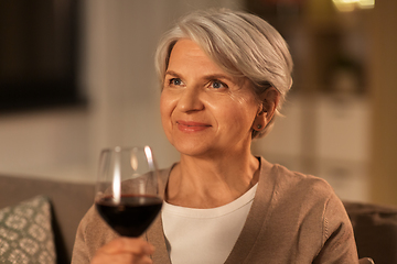 Image showing senior woman drinking red wine at home in evening