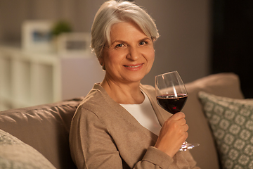 Image showing senior woman drinking red wine at home in evening