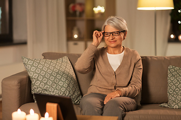 Image showing happy senior woman with tablet pc at home at night