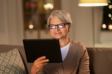 Image showing happy senior woman with tablet pc at home at night