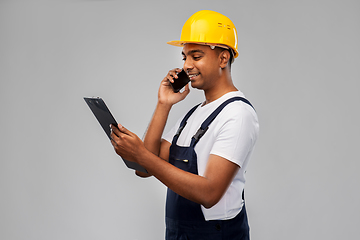 Image showing indian builder with clipboard calling on cellphone