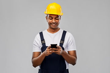 Image showing happy indian or builder in helmet using smartphone