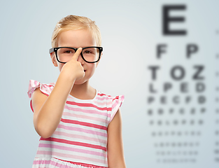 Image showing smiling little girl in glasses over eye test chart