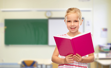 Image showing smiling little girl reading book at school