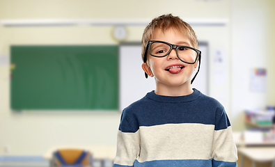 Image showing little boy in glasses showing tongue at school