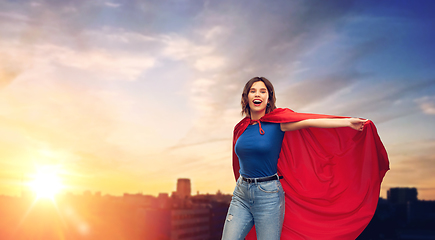 Image showing happy woman in red superhero cape over city sunset