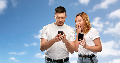 Image showing happy couple in white t-shirts with smartphones